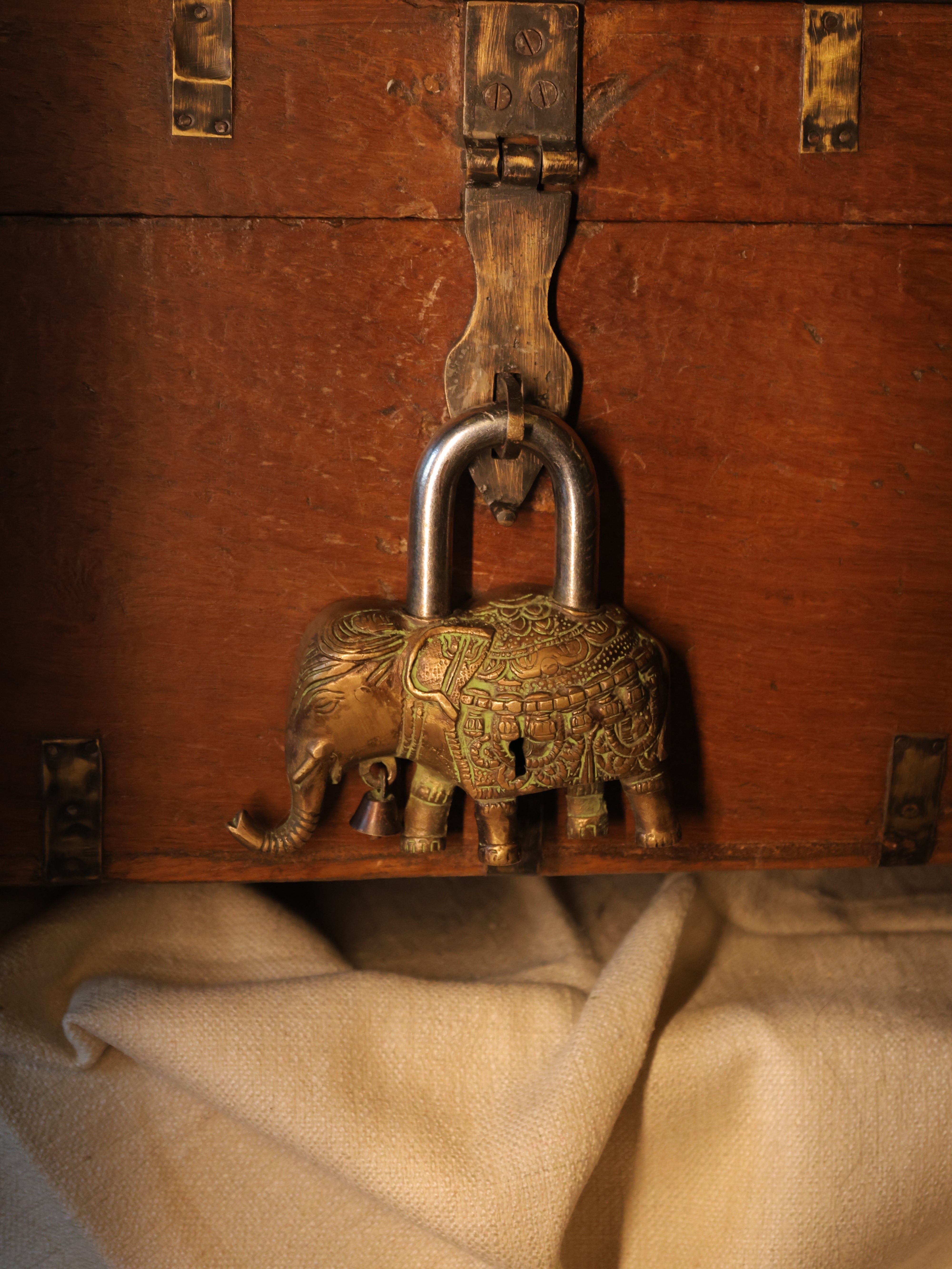 Close-up of a decorative padlock on a wooden surface with beige fabric.
