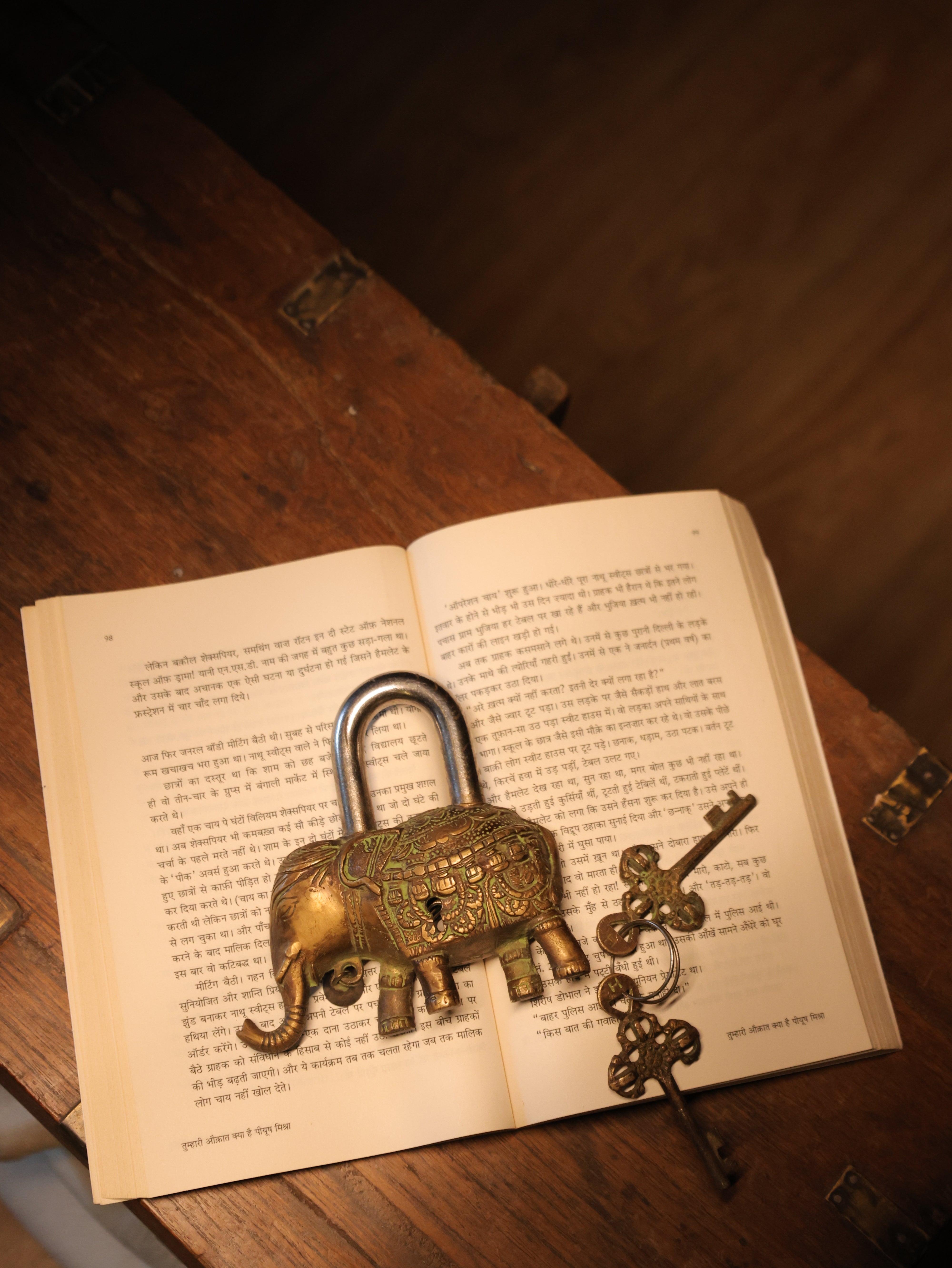 Decorative padlock and keys on an open book with a wooden surface