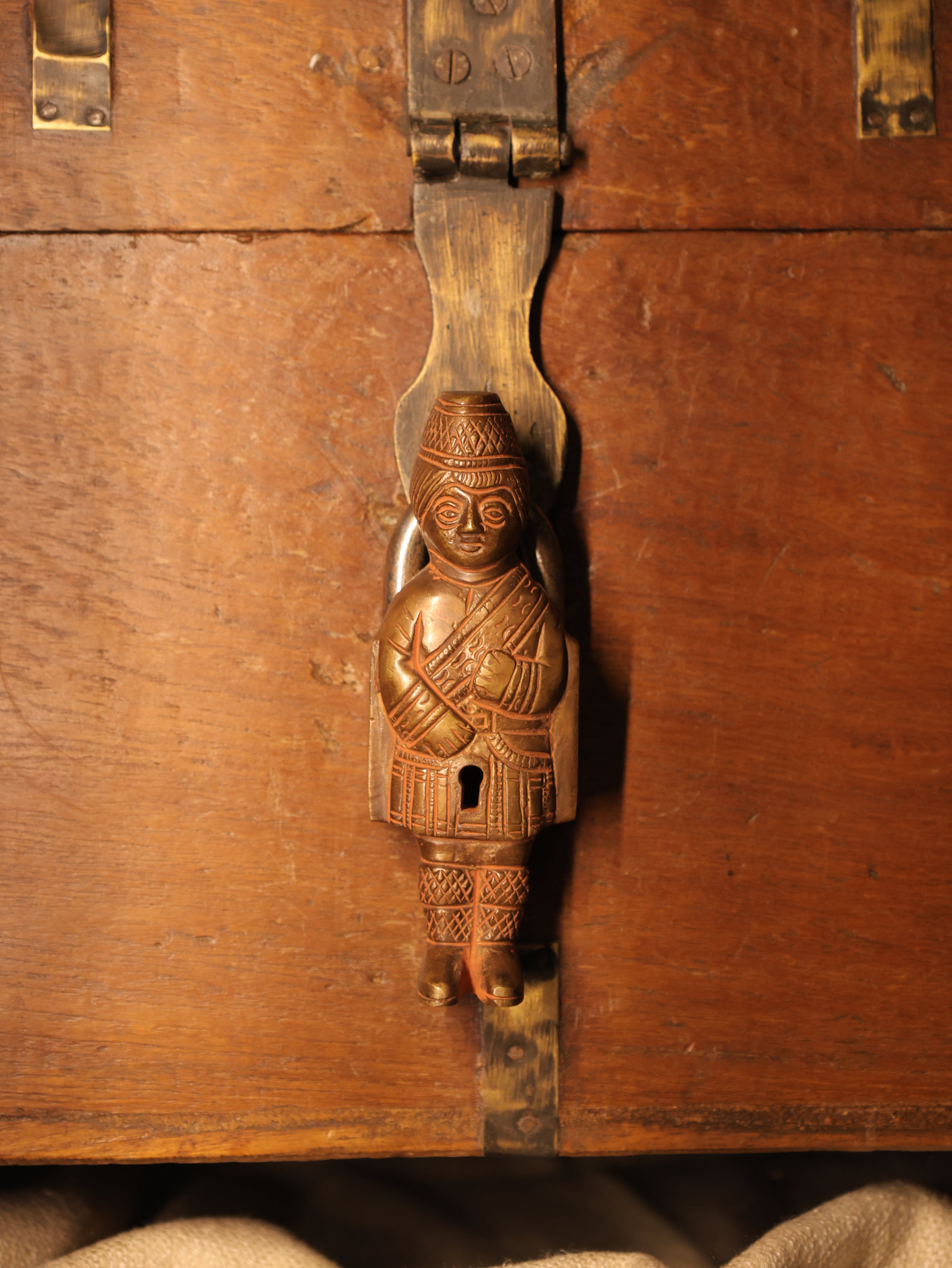 Decorative metal handle with intricate design on a wooden surface
