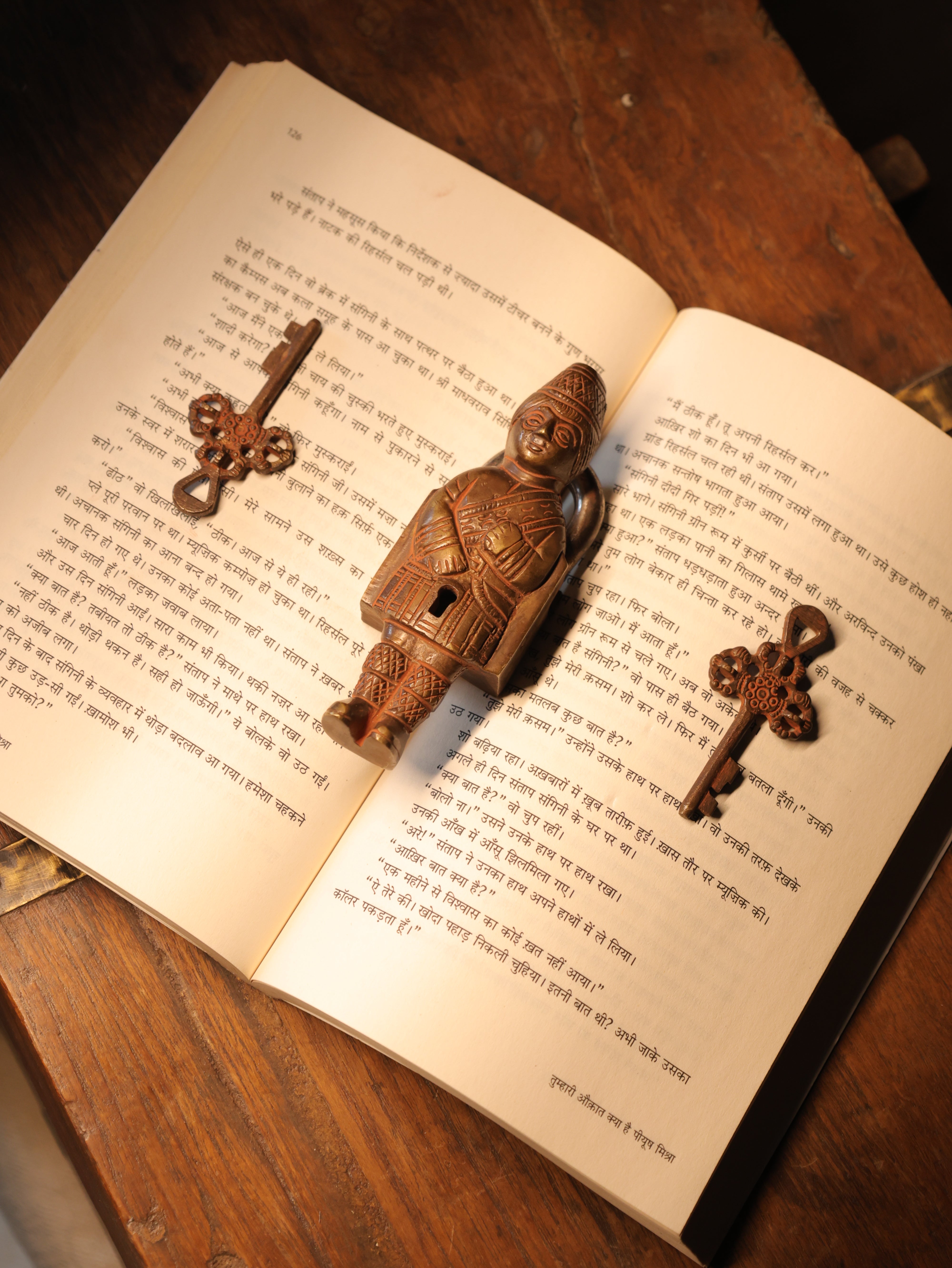 Wooden figurine and keys on an open book with a wooden surface underneath