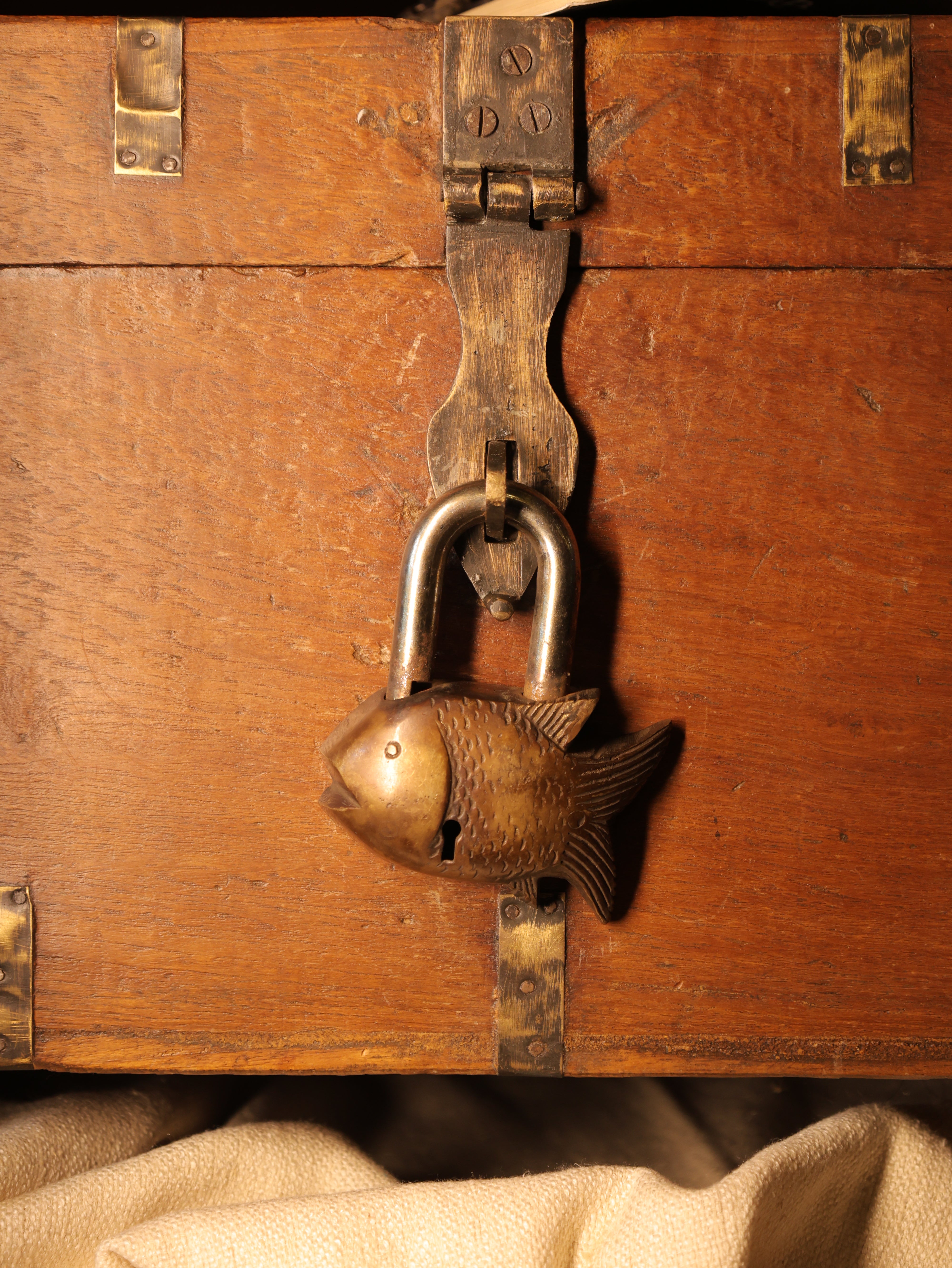 Close-up of a wooden chest with a decorative fish-shaped lock.