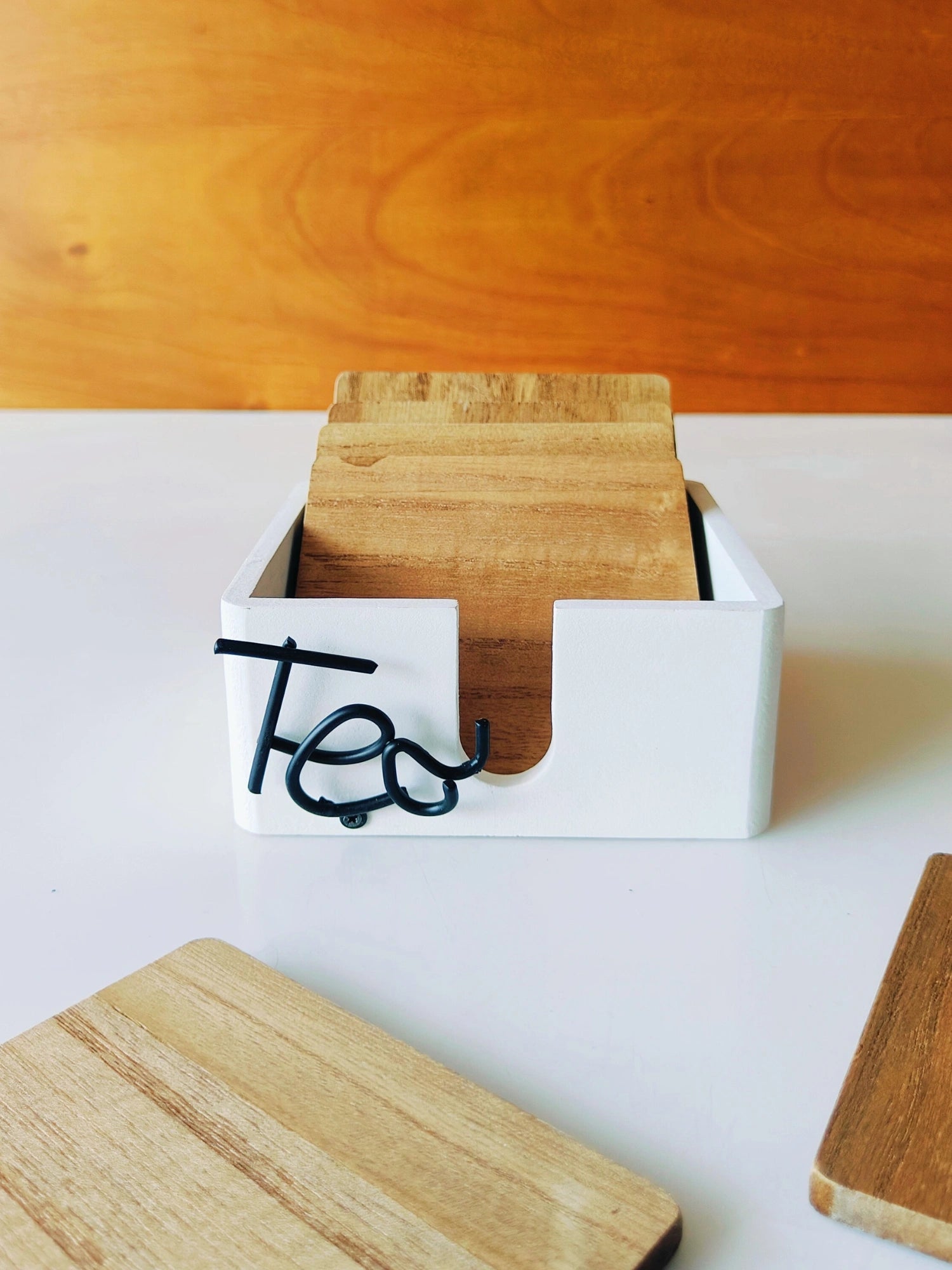 A set of wooden coasters with a unique grain pattern, displayed in a white box with the initial 'T' written on it.